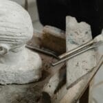 Głowa rzeźby z marmuru i dłuta na drewnianym stole w pracowni