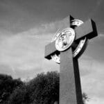 Monumentalny krzyż na tle pochmurnego nieba w czerni i bieli