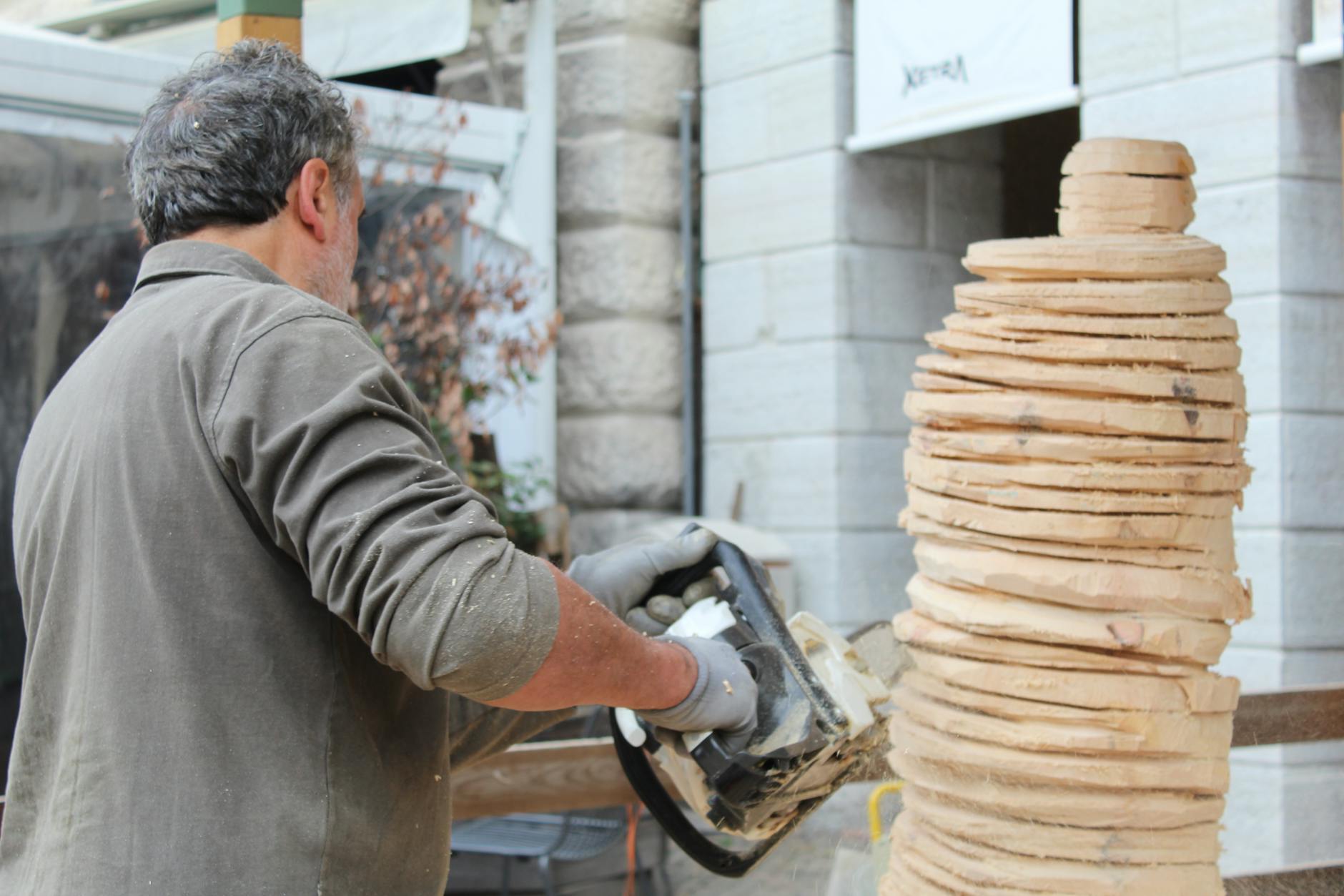 Rzeźbiarz wycina piłą łańcuchową drewnianą rzeźbę na zewnątrz