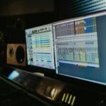 Stanowisko w studiu muzycznym z dwoma monitorami i sprzętem audio