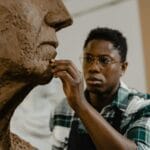 Afroamerykański rzeźbiarz modeluje glinianą rzeźbę w pracowni artystycznej