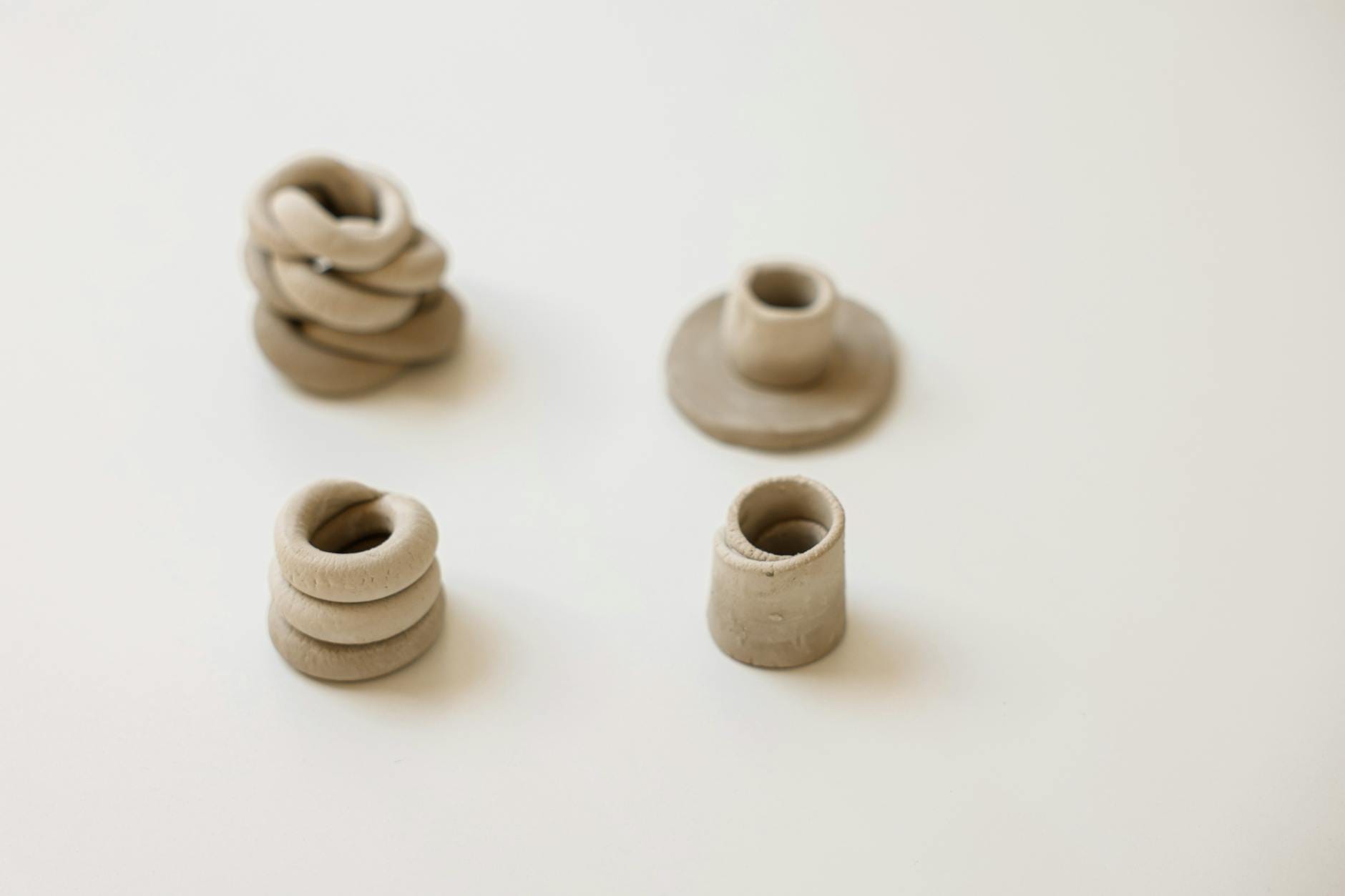 Cztery minimalistyczne rzeźby z gliny na białym tle