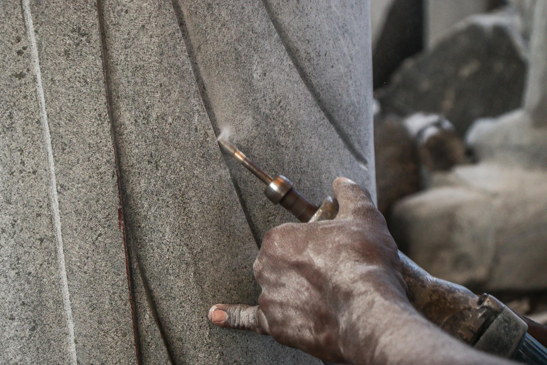Dłonie rzeźbiarza przy pracy nad kamienną kolumną dłutem