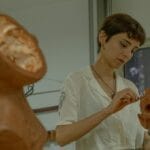 Rzeźbiarka w pracowni modeluje z gliny głowę człowieka