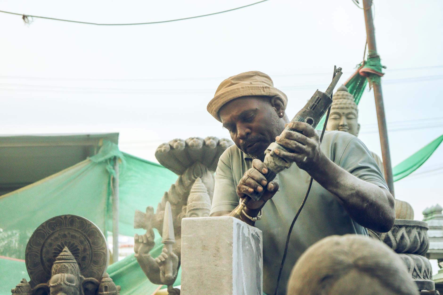 Rzeźbiarz improwizuje dłutem przy kamiennej rzeźbie w plenerowym warsztacie