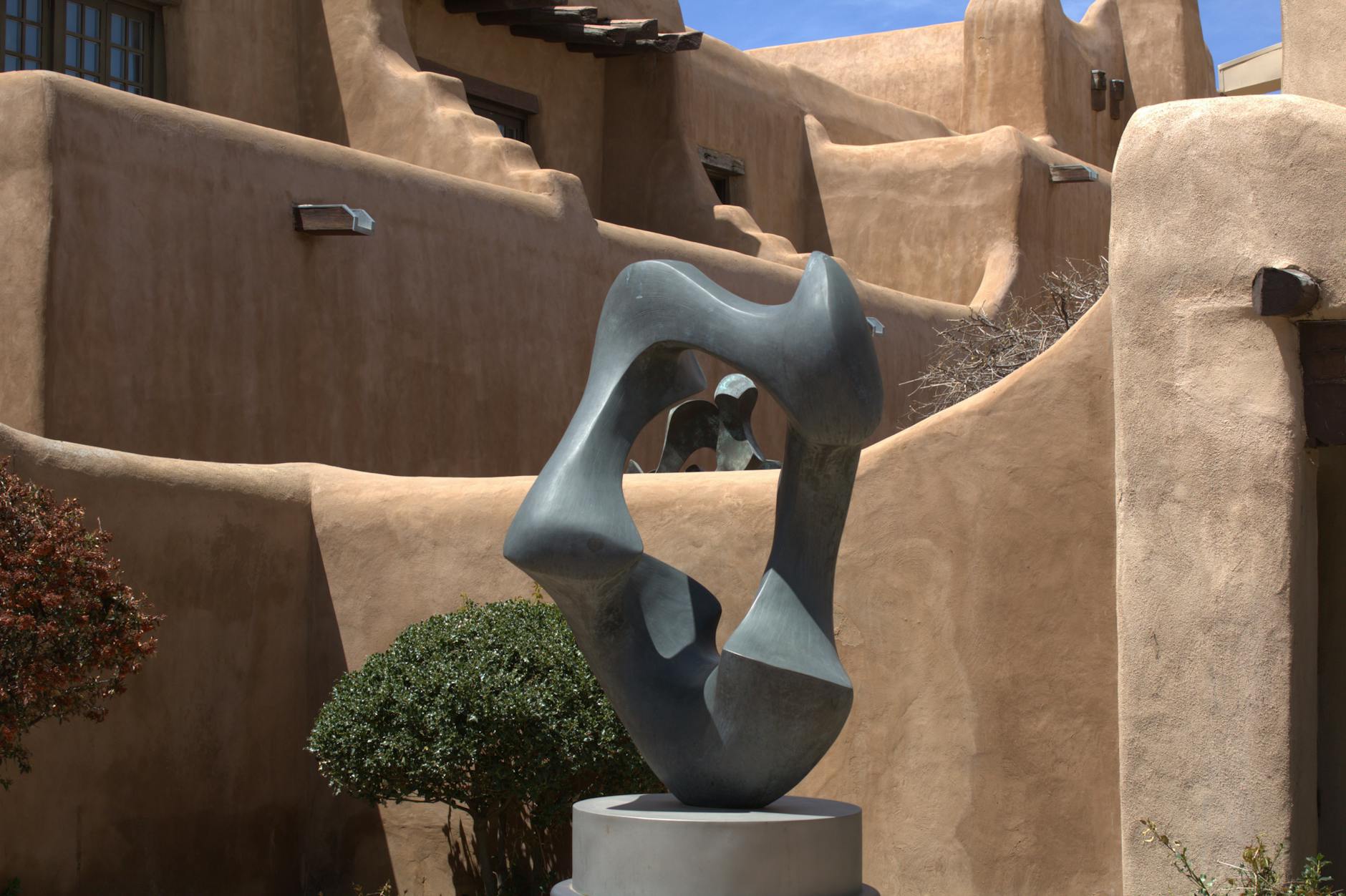 Abstrakcyjna rzeźba na tle glinianych budynków w stylu Pueblo Revival