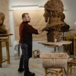 Rzeźbiarz modeluje gliniany popiersie w jasnej pracowni